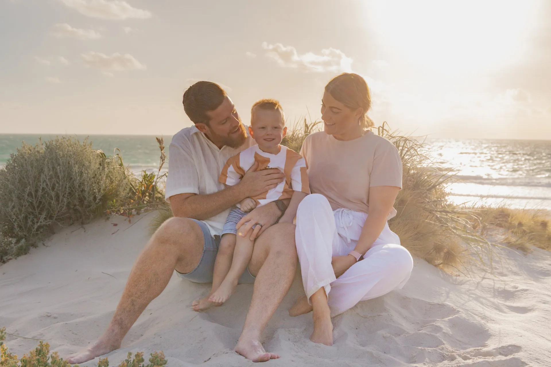 Haley and her family sitting together on a beach dune at sunset
